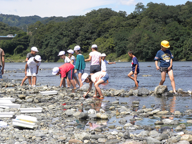 写真：川辺で体験学習を受けている小学生たち